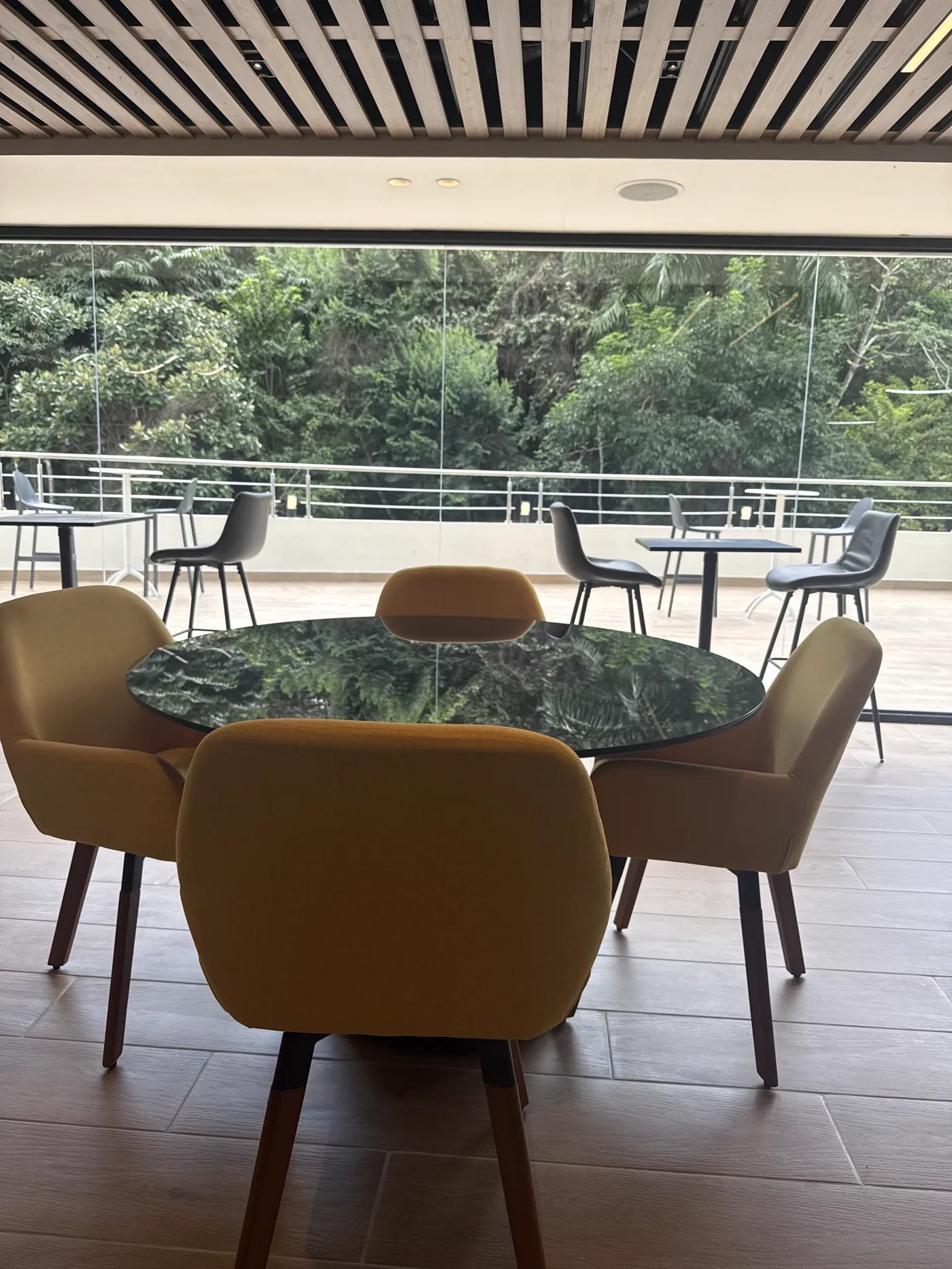 Comedor del lounge con sillas amarillas frente al ventanal con vista al bosque